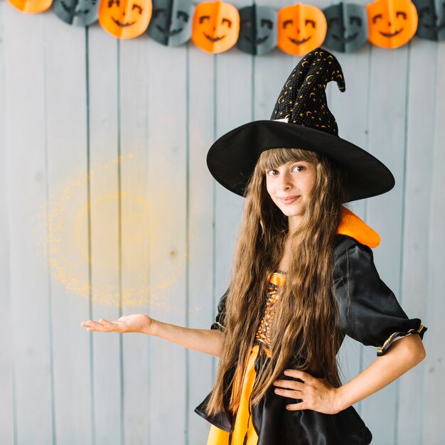 Joven bruja mostrando brujería en Halloween