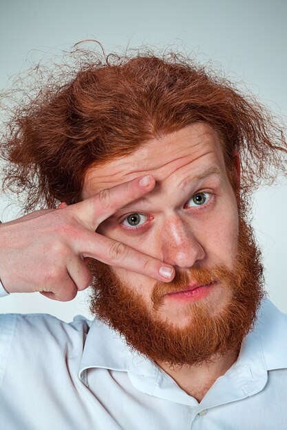 El joven con cabello largo rojo mirando a cámara, abriendo los ojos