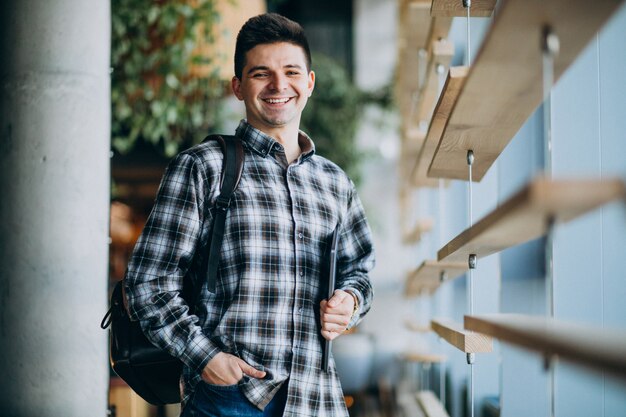 Joven en un café de pie byy la ventana y hablando por teléfono