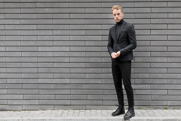 Joven en la calle cerca de una pared gris