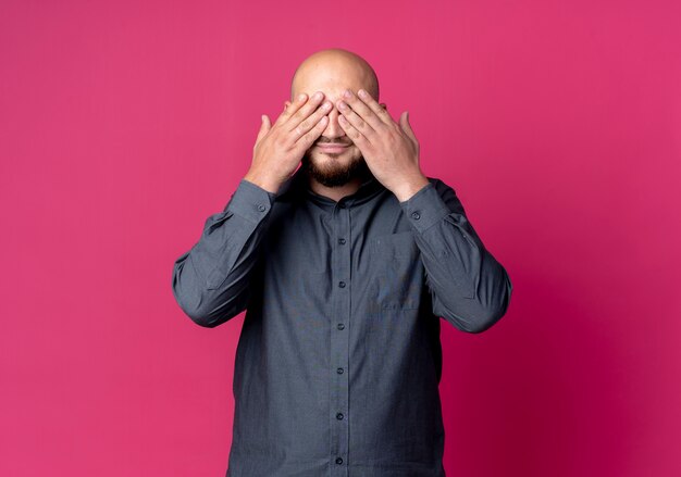 Foto gratuita joven calvo call center hombre cerrando los ojos con las manos aisladas sobre fondo carmesí con espacio de copia