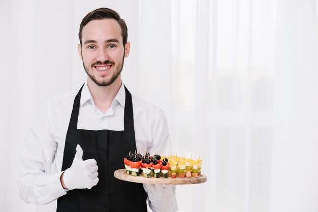 Joven camarero mostrando aperitivos