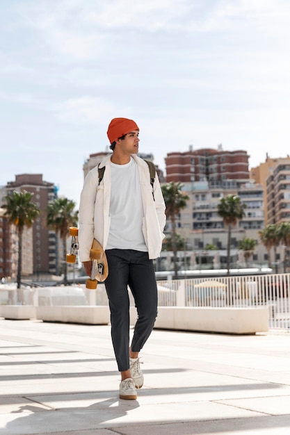 Joven caminando sosteniendo su patineta