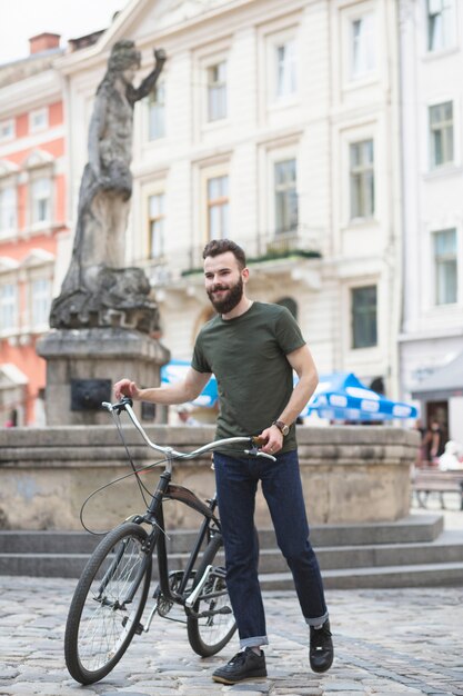 Joven caminando con su bicicleta en frente de la estatua