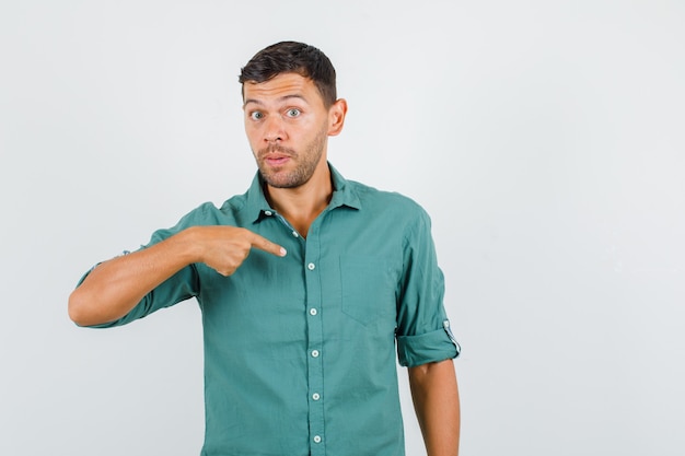 Joven en camisa apuntando a sí mismo en gesto de cuestionamiento