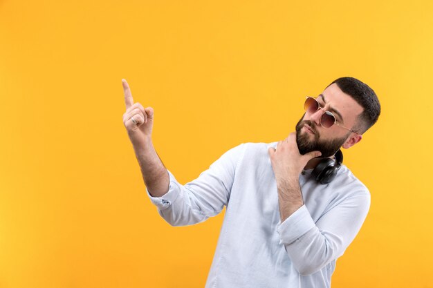 Joven de camisa blanca con barba, gafas de sol y auriculares negros