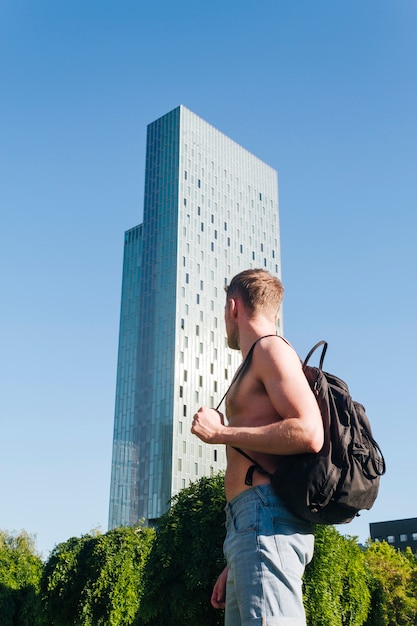 Joven sin camisa con mochila al aire libre