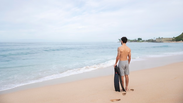 Joven sin camisa en la playa con equipo de buceo