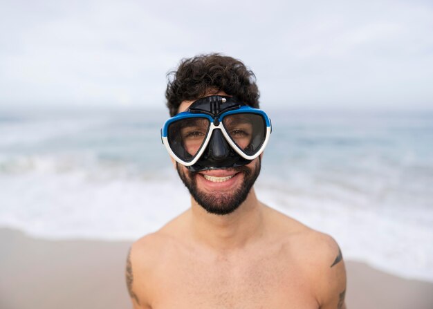 Foto gratuita joven sin camisa en la playa con equipo de buceo