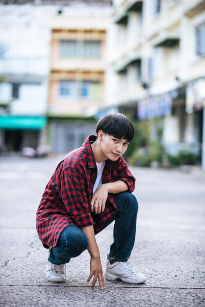 Un joven con una camisa a rayas sentado en la calle