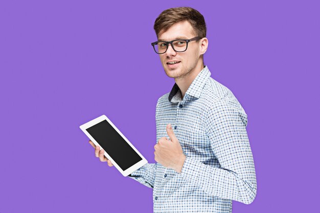 El joven en una camisa trabajando en la computadora portátil sobre fondo lila