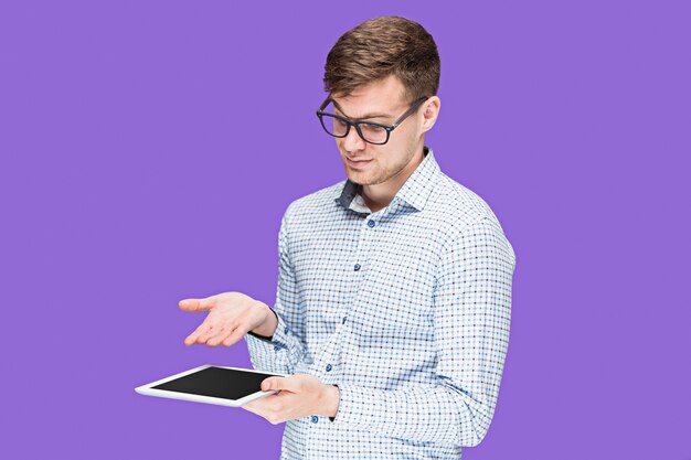 Joven en una camisa trabajando en un portátil sobre fondo lila studio