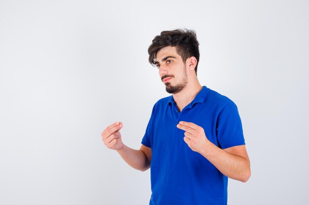 Joven en camiseta azul mostrando dinero sesture y mirando serio