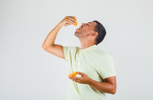 Joven en camiseta comiendo una de las rodajas de naranja