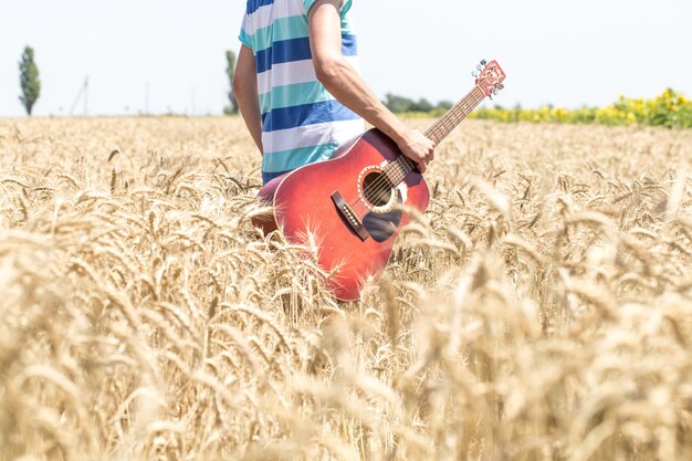 Joven en un campo de trigo con una guitarra