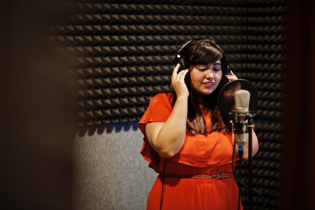 Joven cantante asiática con micrófono grabando una canción en un estudio de grabación de música