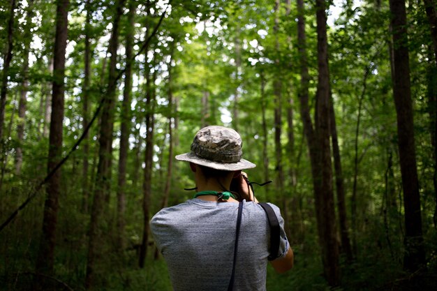 Joven casual con gorra verde en un parque de la selva hace fotos de la naturaleza