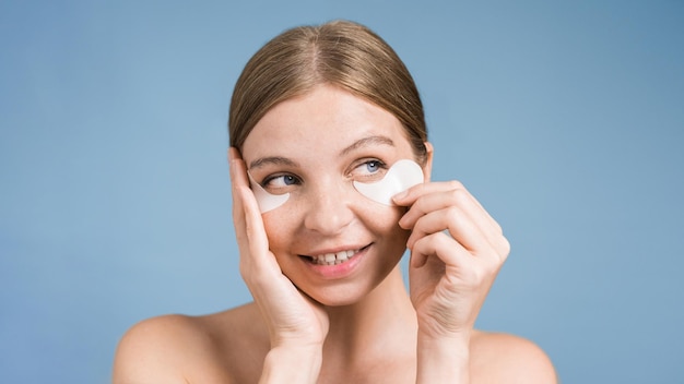 Foto gratuita una joven caucásica colocando parches debajo de sus ojos.