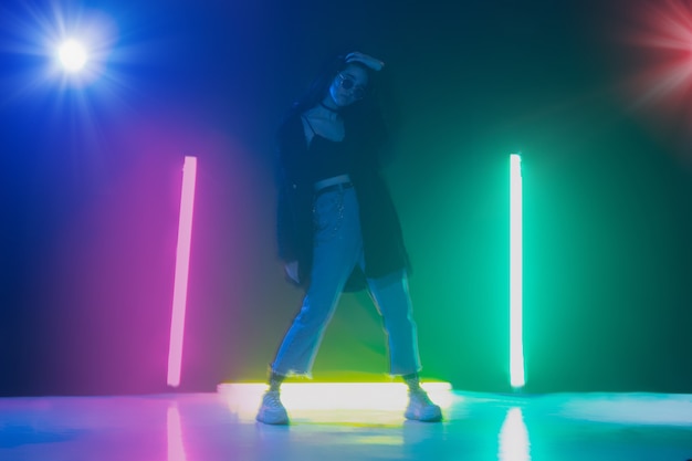 Joven caucásica posando con estilo en la sala de luz de neón