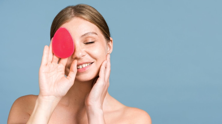 Foto gratuito una joven caucásica sonriente está haciendo un masaje facial con un depurador facial