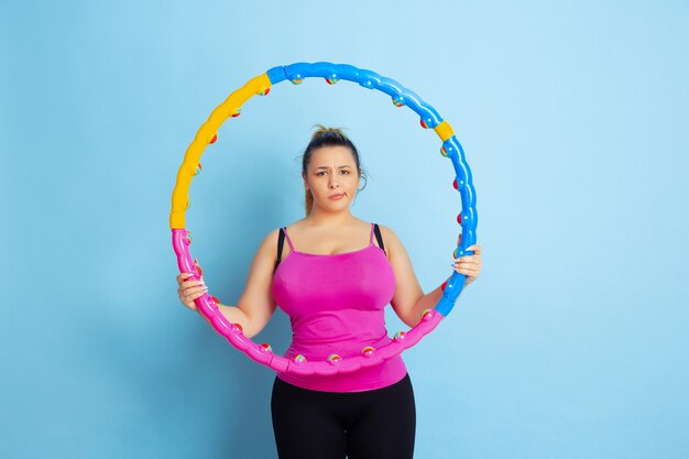 Joven caucásica de talla grande modelo femenino de formación sobre fondo azul.