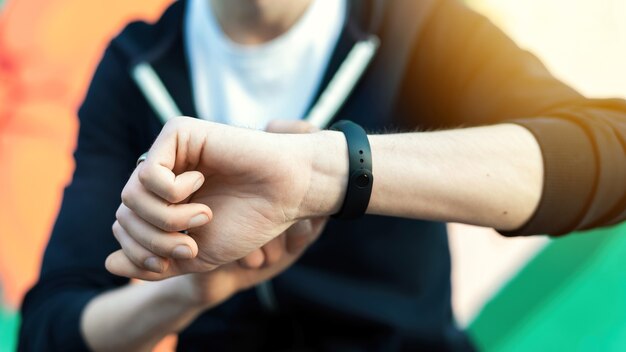 Joven caucásico está en su pulsera de fitness sobre fondo multicolor