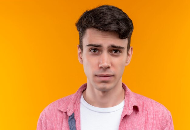 Joven caucásico vistiendo camisa rosa sobre pared naranja aislada