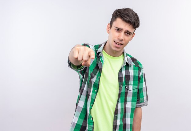 Foto gratuita joven caucásico vistiendo camisa verde que le muestra gesto en la pared blanca aislada