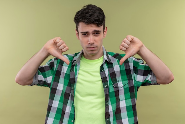 Foto gratuita joven caucásico vistiendo camisa verde se señala a sí mismo en la pared verde aislada