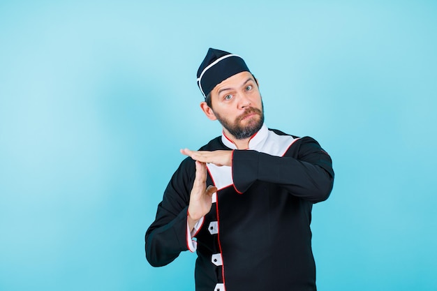 El joven chef está mostrando gestos con las manos sobre fondo azul.