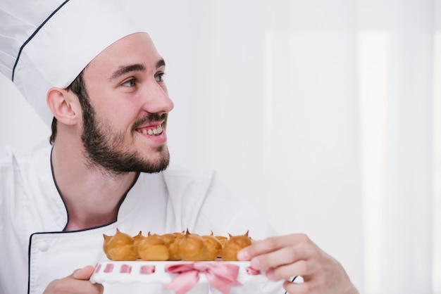 Foto gratuita joven chef con merengue mirando a otro lado