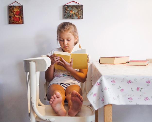 Foto gratuita joven chica bonita libro de lectura en la mesa