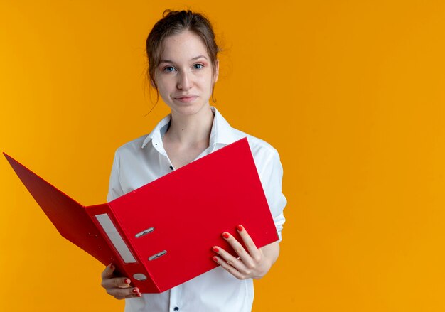 Joven chica rusa rubia molesta tiene carpeta de archivos en naranja con espacio de copia