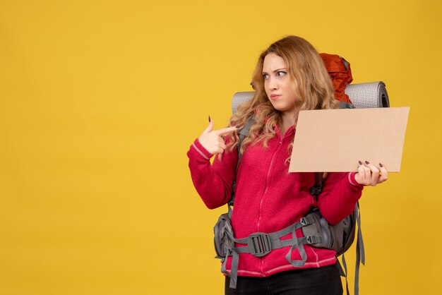 Joven chica viajera sorprendida recogiendo su equipaje mostrando espacio libre para escribir apuntando a sí misma