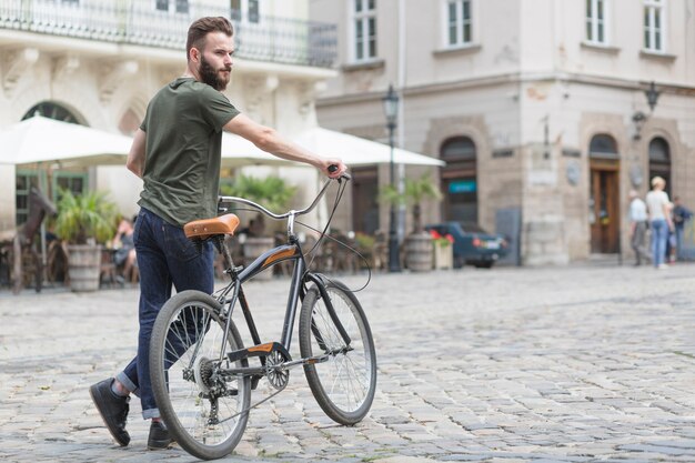 Joven ciclista masculino con su bicicleta en la calle