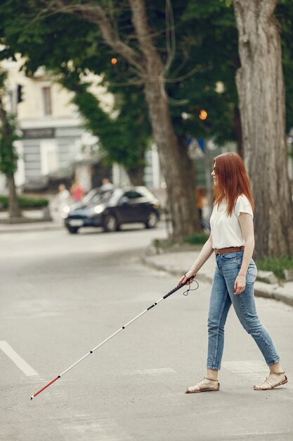 Joven ciego con bastón largo caminando en una ciudad