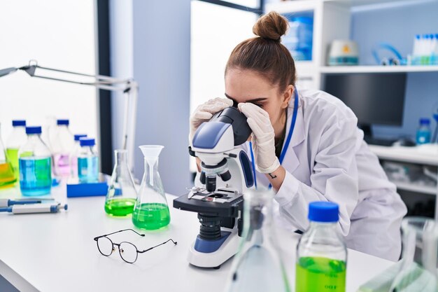 Joven científica usando microscopio en el laboratorio