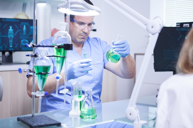 Joven científico sosteniendo dos tubos de ensayo en un laboratorio de investigación. Biólogo trabajando.