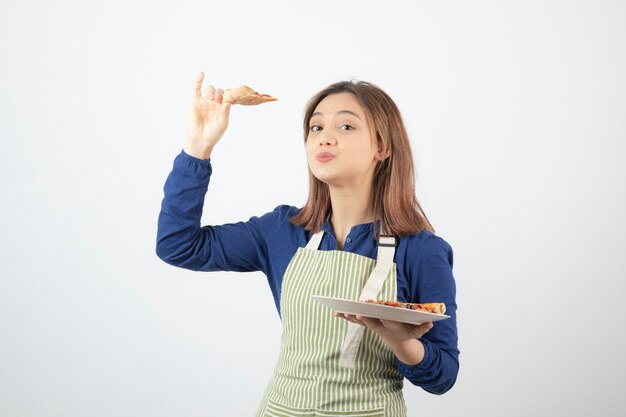 joven cocinera sosteniendo un plato de deliciosa pizza.