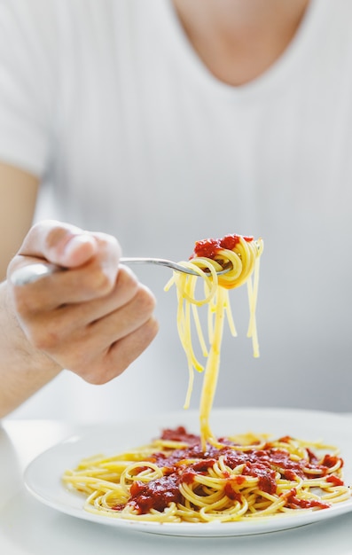 Foto gratuita joven comiendo sabroso espagueti con salsa de tomate. de cerca.