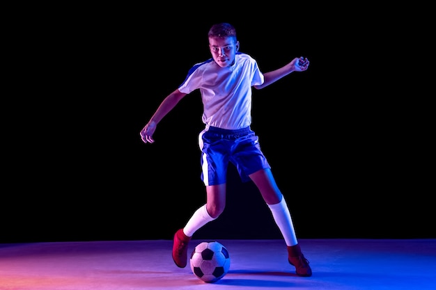 Joven como jugador de fútbol o fútbol en la pared oscura