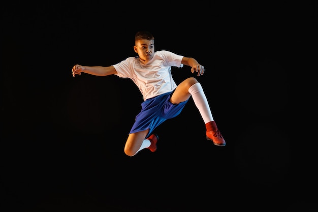 Joven como jugador de fútbol o fútbol en la pared oscura