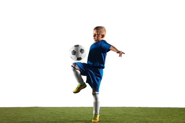 Joven como un jugador de fútbol o fútbol en ropa deportiva haciendo una finta o una patada con el balón para un gol sobre fondo blanco.