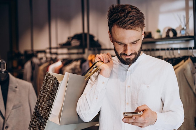 Joven comprando en la tienda de ropa masculina y hablando por teléfono