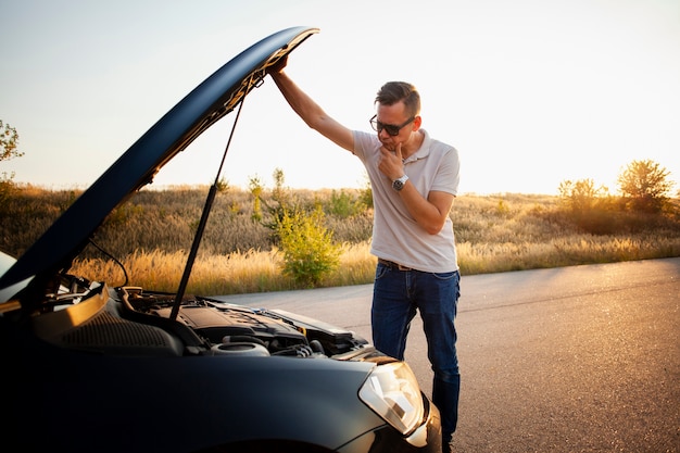 Joven comprobando el motor del coche