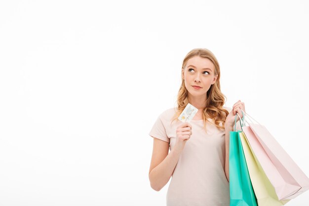 Joven concentrada con tarjeta de débito y bolsas de compras.