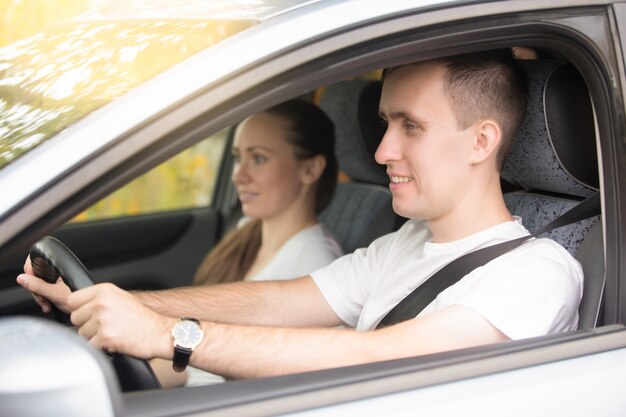 Joven conducción y mujer sentada cerca en el coche