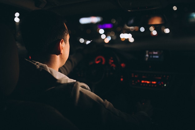 Joven conduciendo su automóvil por la noche