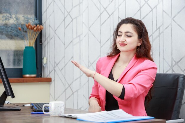 Joven confiada sentada detrás del escritorio Foto de alta calidad