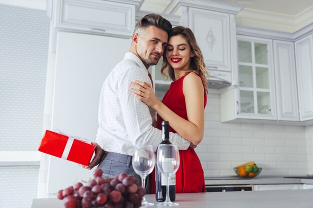 Joven confiado mientras se esconde presente para su encantadora mujer, concepto de día de San Valentín